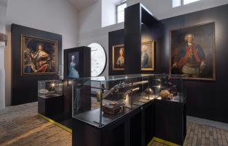 Das Foto zeigt einen Raum der Brandenburg - Ausstellung im Brandenburg Museum für Zukunft, Gegenwart und Geschichte. Zu sehen sind Gemälde und Vitrinen mit Ausstellungsstücken.